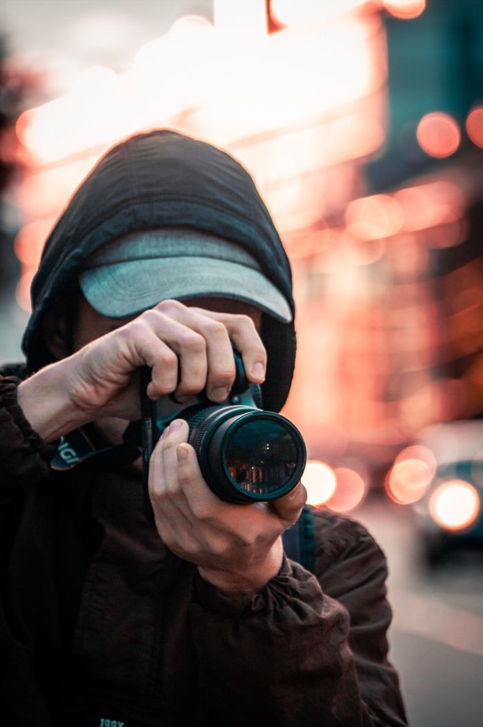 Close-up of a person taking photos with blurred city lights in the background.