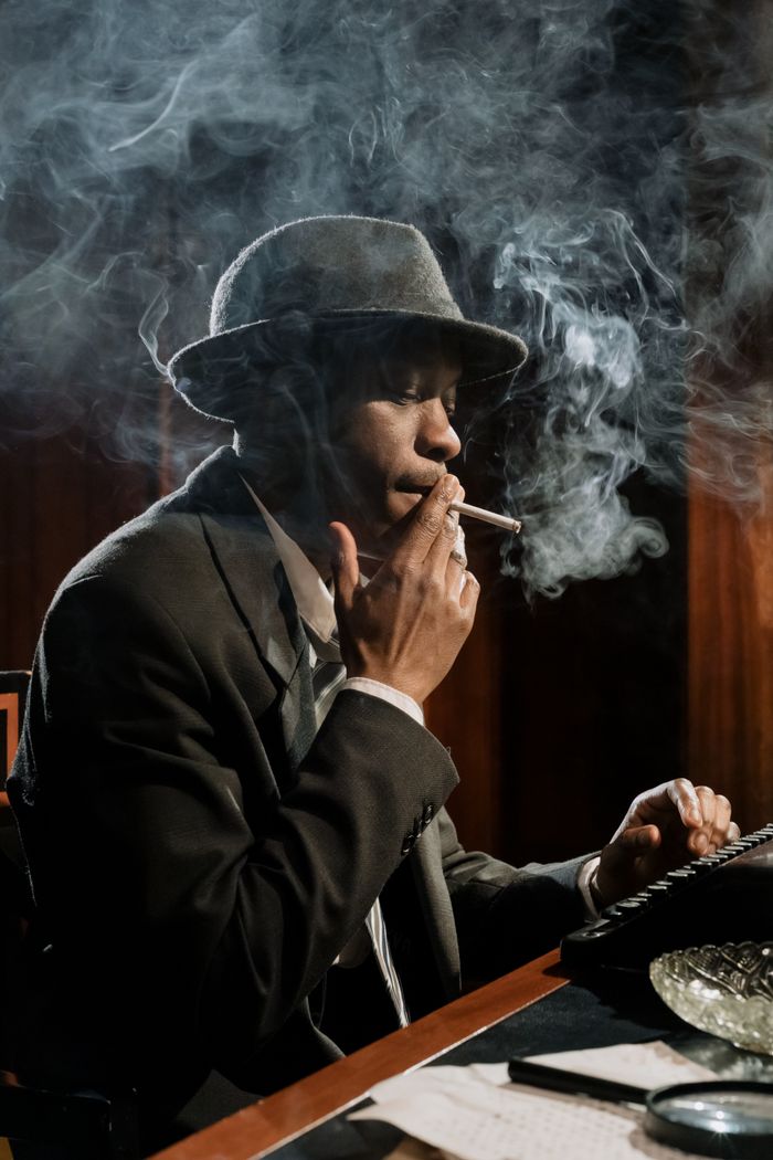 Moody scene featuring a detective smoking while typing on a vintage typewriter.